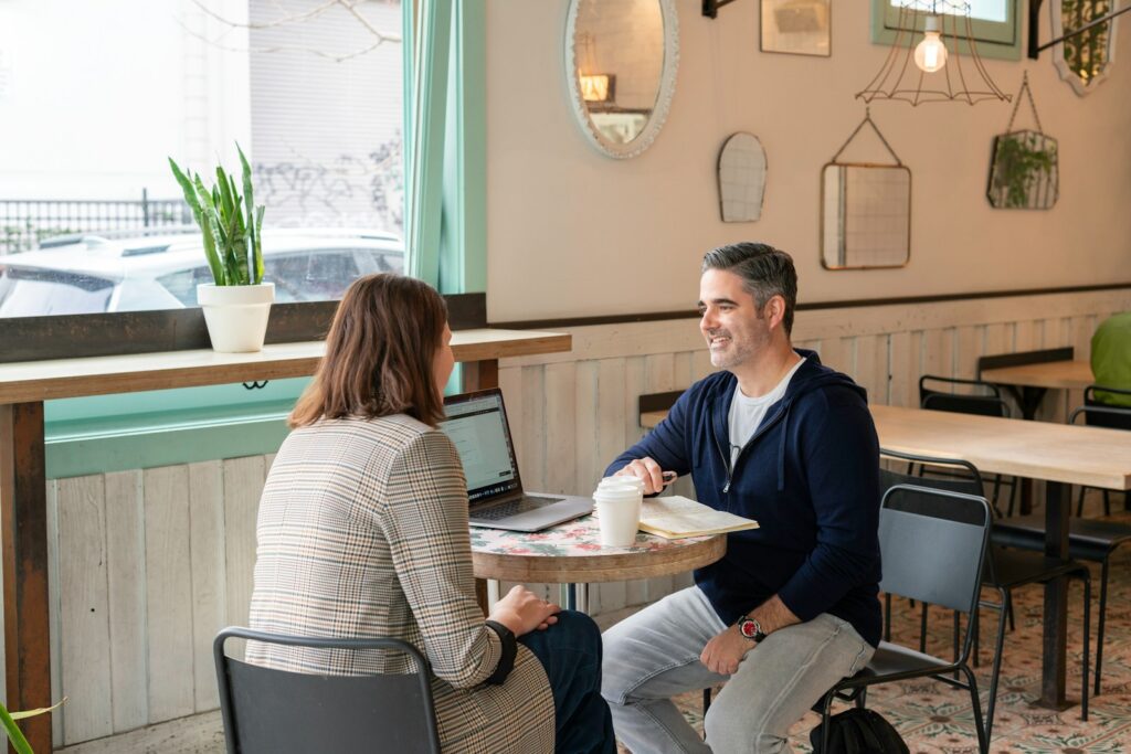 man in black sweater sitting beside woman in white and black striped long sleeve shirt